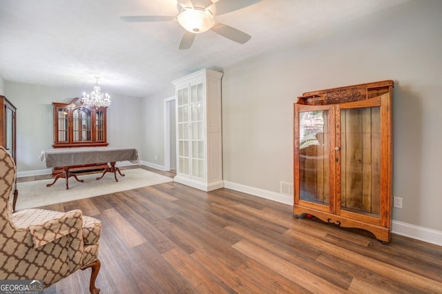 sitting room featuring ceiling fan with notable chandelier, visible vents, baseboards, and wood finished floors