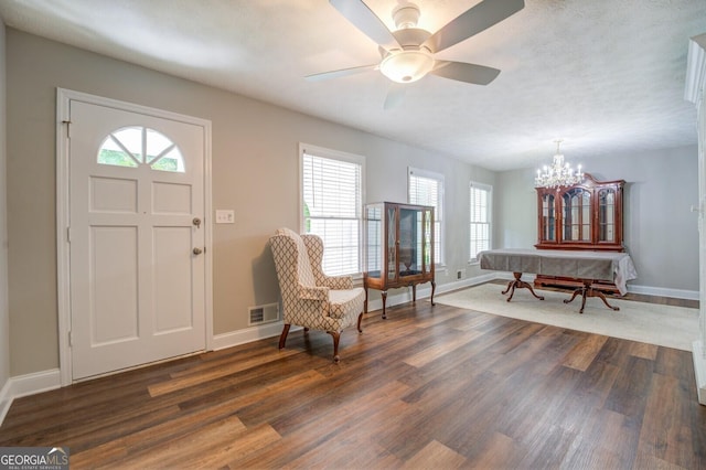 interior space with dark wood-style floors, visible vents, baseboards, and ceiling fan with notable chandelier