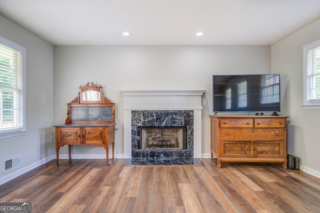 living area featuring baseboards, visible vents, wood finished floors, a fireplace, and recessed lighting