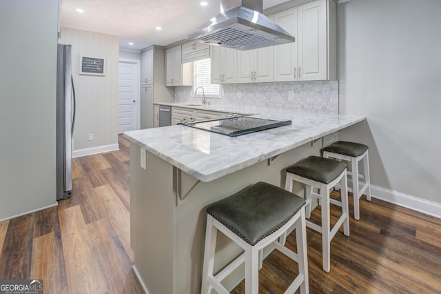 kitchen featuring decorative backsplash, a peninsula, light stone countertops, stainless steel appliances, and exhaust hood