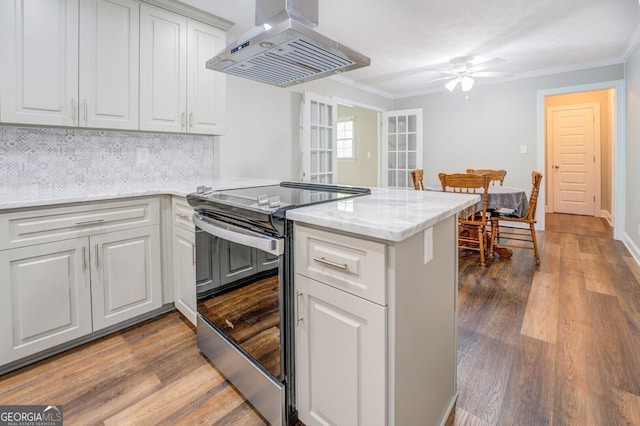 kitchen with stainless steel electric range oven, crown molding, wood finished floors, and island range hood