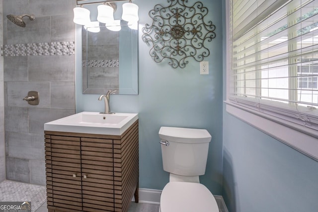 full bathroom with toilet, baseboards, tiled shower, and vanity