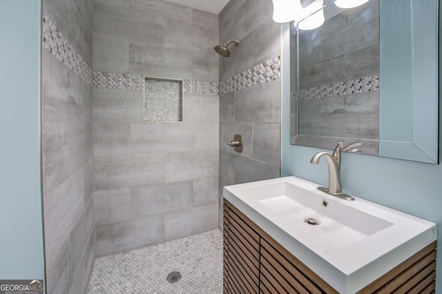 full bathroom with tiled shower and vanity