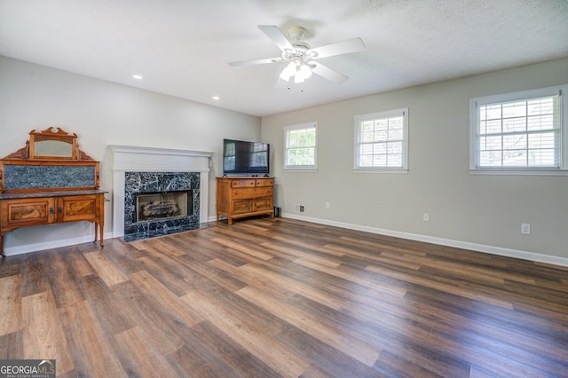 living room featuring recessed lighting, a premium fireplace, wood finished floors, a ceiling fan, and baseboards