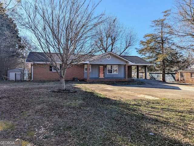 view of front of property featuring brick siding, board and batten siding, fence, an attached carport, and driveway