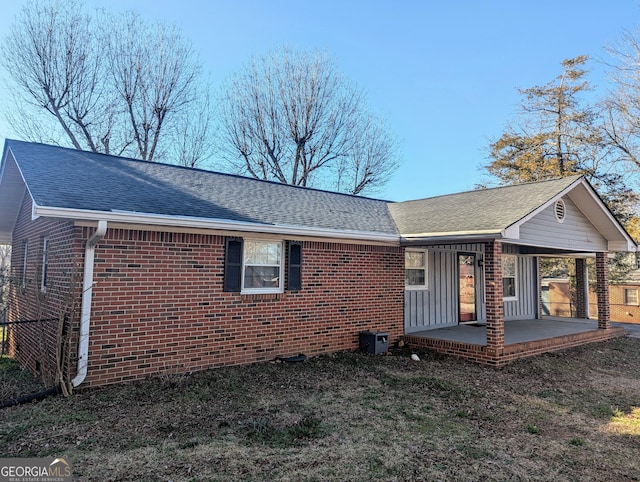 exterior space with a carport, brick siding, and a shingled roof