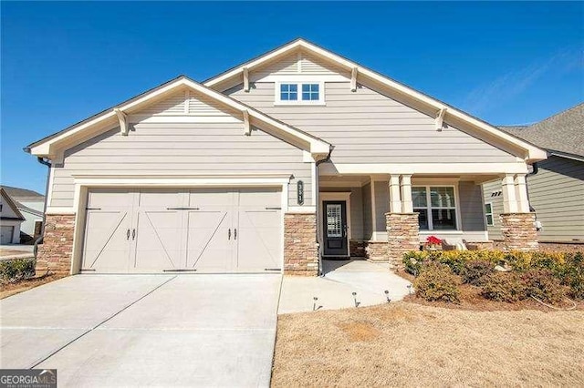 craftsman house featuring driveway, stone siding, and an attached garage