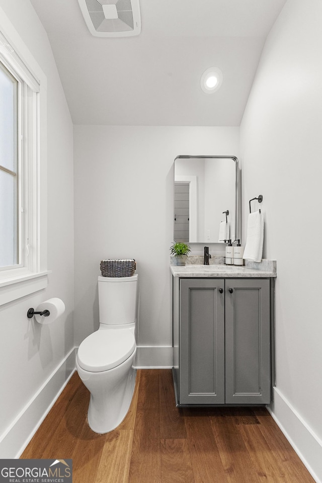 bathroom with visible vents, toilet, vanity, wood finished floors, and baseboards