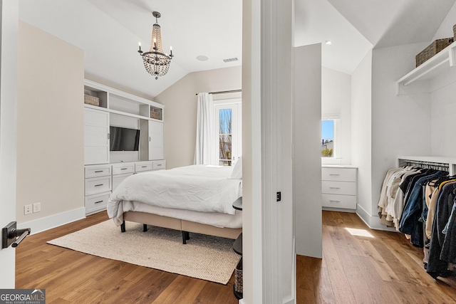 bedroom featuring lofted ceiling, baseboards, visible vents, and hardwood / wood-style floors