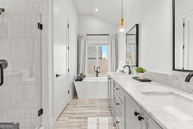 full bathroom with lofted ceiling, a shower stall, a freestanding bath, and a sink