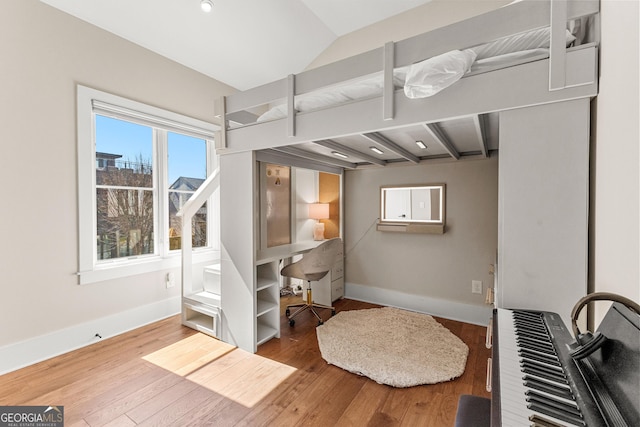 bedroom with lofted ceiling, wood finished floors, and baseboards