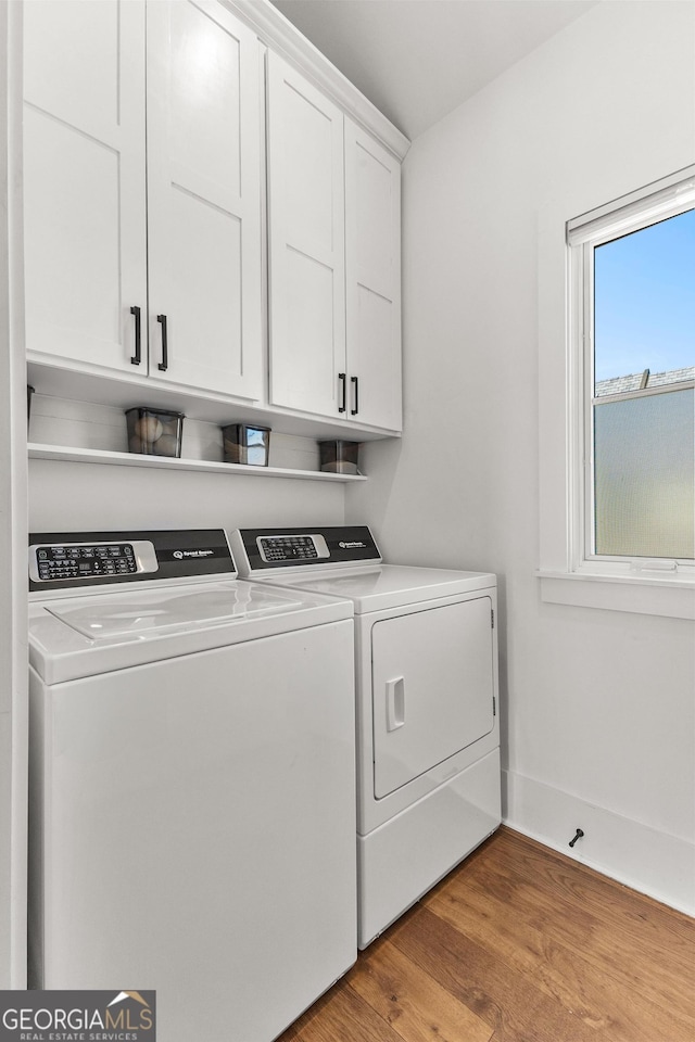 laundry room with light wood finished floors, washing machine and dryer, cabinet space, and baseboards