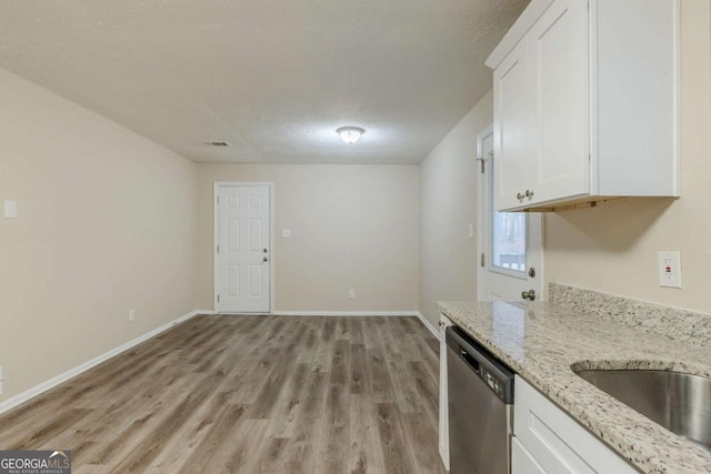 kitchen with white cabinets, dishwasher, light wood finished floors, and light stone countertops