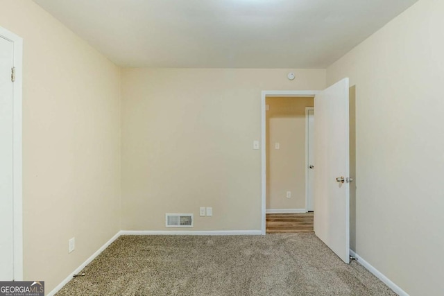 empty room with baseboards, visible vents, and carpet flooring