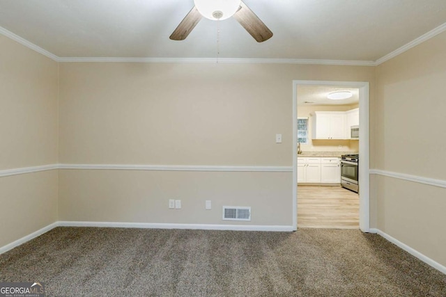 spare room featuring ornamental molding, visible vents, light carpet, and baseboards