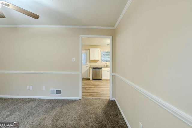 unfurnished room with visible vents, ornamental molding, a ceiling fan, light carpet, and baseboards