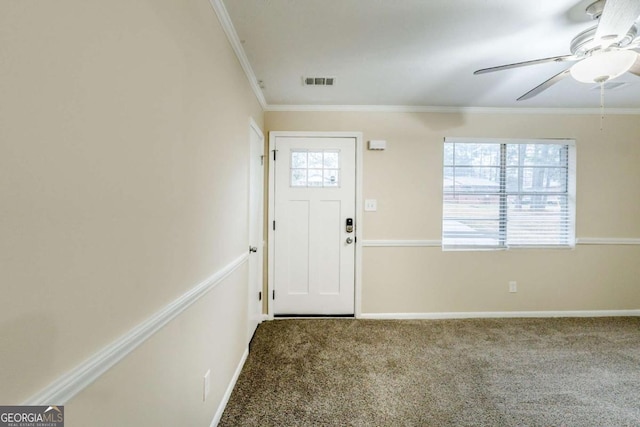 carpeted foyer entrance with ornamental molding, a ceiling fan, visible vents, and baseboards