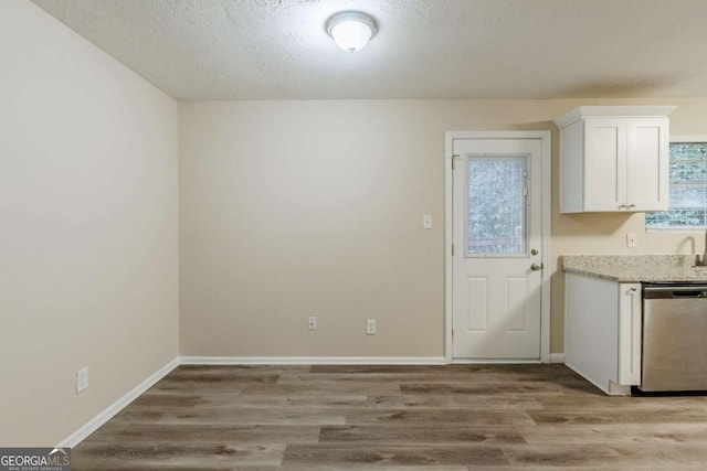 unfurnished dining area with a textured ceiling, baseboards, and wood finished floors