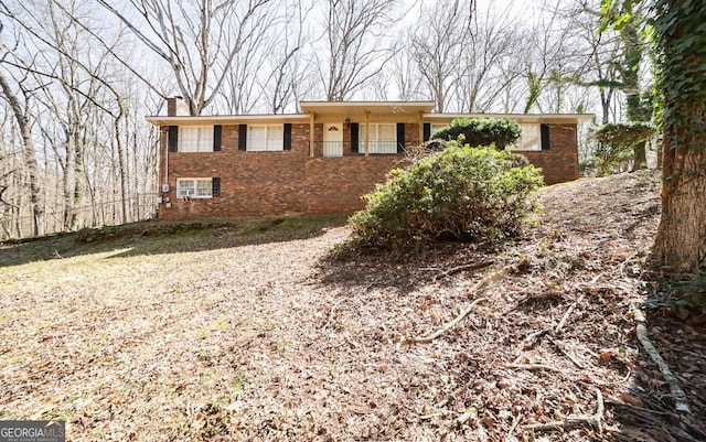 ranch-style house featuring a chimney and brick siding