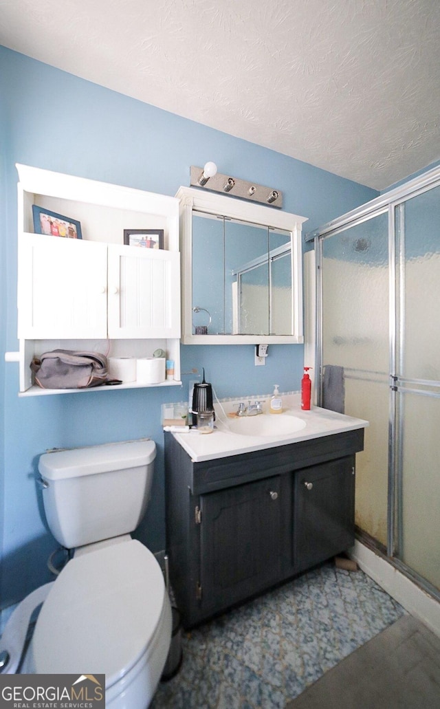 bathroom featuring toilet, a textured ceiling, a shower stall, and vanity