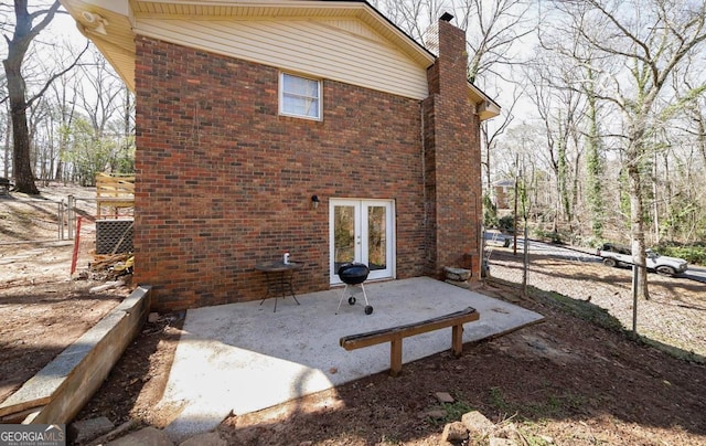 exterior space with french doors, brick siding, and a chimney