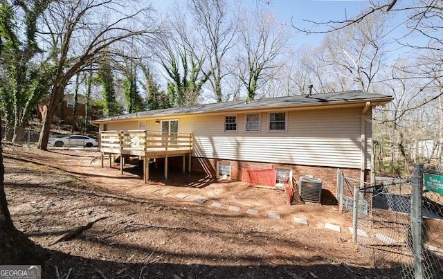 rear view of property featuring fence, a wooden deck, and central AC unit