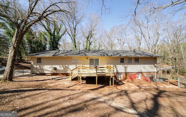 back of property with driveway, a wooden deck, and stairs