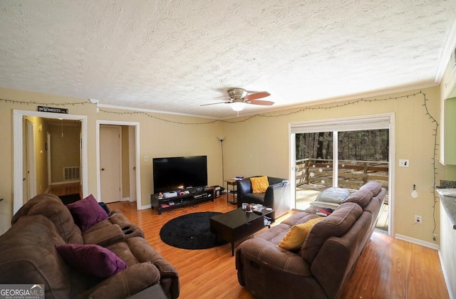 living area featuring a textured ceiling, baseboards, and wood finished floors