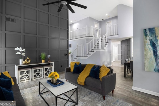 living area with visible vents, a decorative wall, stairway, and wood finished floors