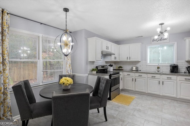 kitchen with light stone counters, a notable chandelier, stainless steel electric stove, backsplash, and white cabinets