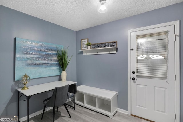 office area featuring a textured ceiling, baseboards, and wood finished floors