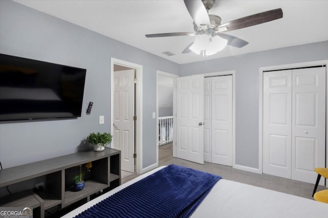 bedroom featuring baseboards, visible vents, a ceiling fan, carpet flooring, and multiple closets