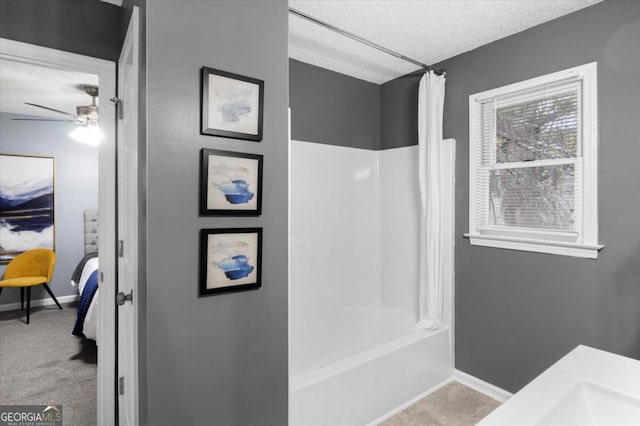 ensuite bathroom with shower / bath combo with shower curtain, ceiling fan, a textured ceiling, ensuite bath, and baseboards