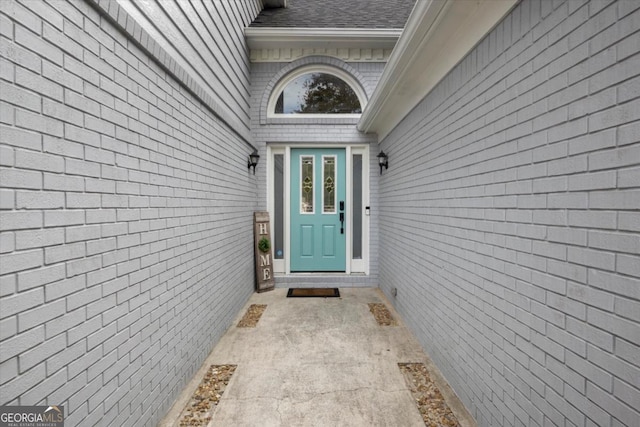 view of exterior entry with roof with shingles