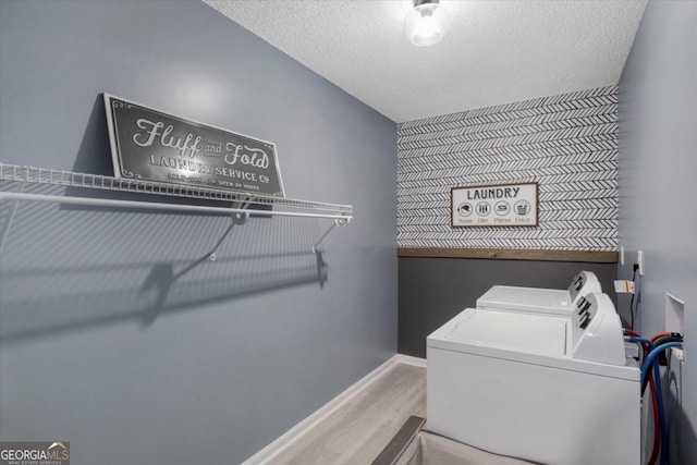 clothes washing area featuring laundry area, baseboards, wood finished floors, independent washer and dryer, and a textured ceiling