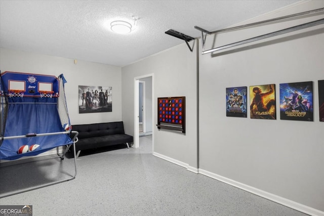 recreation room with baseboards, a textured ceiling, and speckled floor