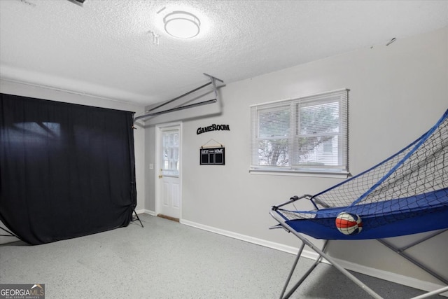 rec room with a wealth of natural light, a textured ceiling, baseboards, and speckled floor