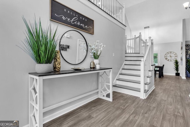 foyer featuring stairs, a high ceiling, baseboards, and wood finished floors