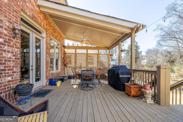 wooden deck with outdoor dining space, a grill, and a ceiling fan