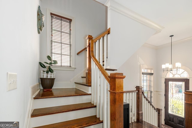 stairs featuring a notable chandelier and crown molding