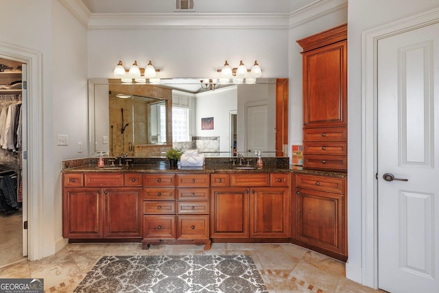 bathroom featuring double vanity, a tile shower, crown molding, a walk in closet, and a sink