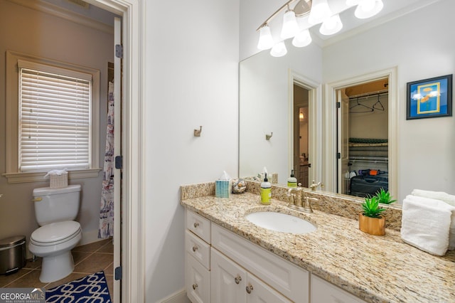 full bathroom featuring a walk in closet, toilet, vanity, tile patterned flooring, and baseboards