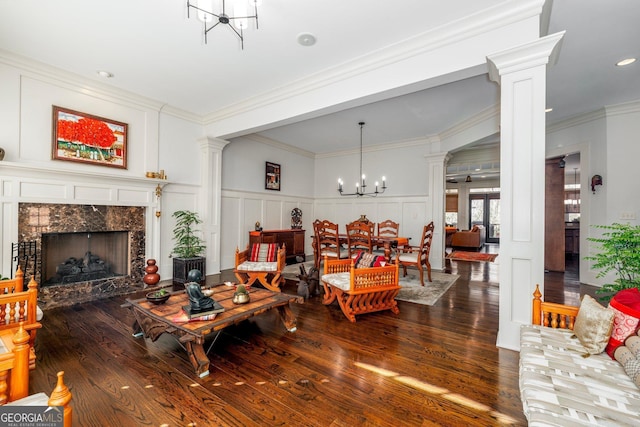 living area with decorative columns, a premium fireplace, a chandelier, and a decorative wall