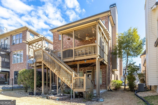 rear view of house with a chimney, stairs, a wooden deck, central AC, and brick siding