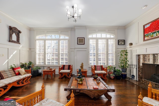 living area featuring a notable chandelier, ornamental molding, a decorative wall, and dark wood-style flooring