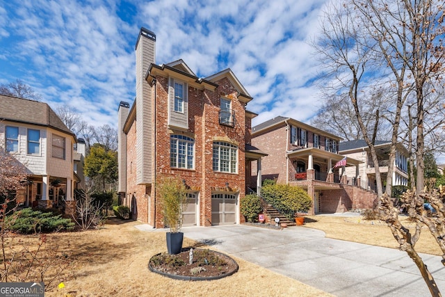 view of front facade with brick siding, driveway, a chimney, and an attached garage