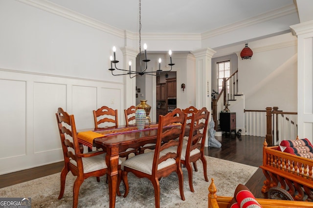 dining area with dark wood-style floors, decorative columns, ornamental molding, and a decorative wall