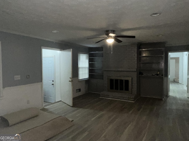 unfurnished living room with built in shelves, a brick fireplace, ceiling fan, a textured ceiling, and wood finished floors