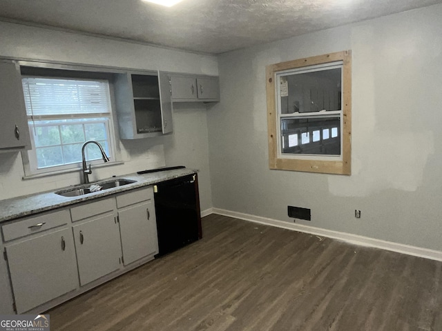 kitchen featuring black dishwasher, light countertops, dark wood-type flooring, a sink, and baseboards