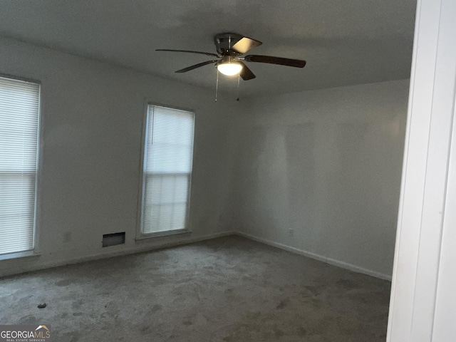 carpeted empty room with baseboards and a ceiling fan